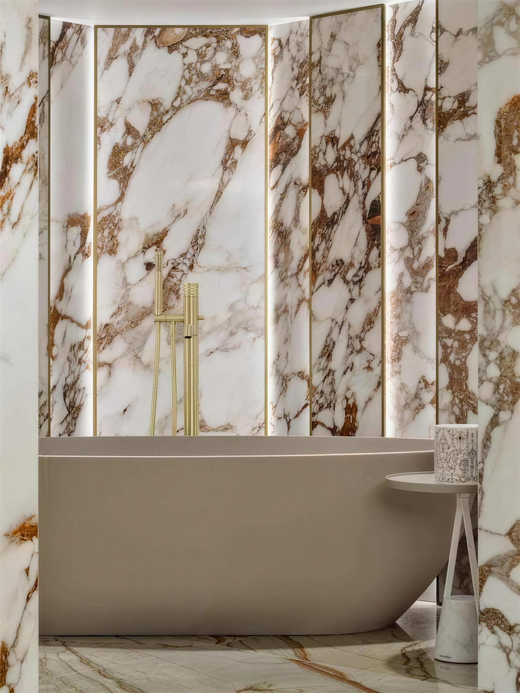 Bathroom in the Faura showroom clad in Calacatta Viola marble with a freestanding tub and brushed brass fittings